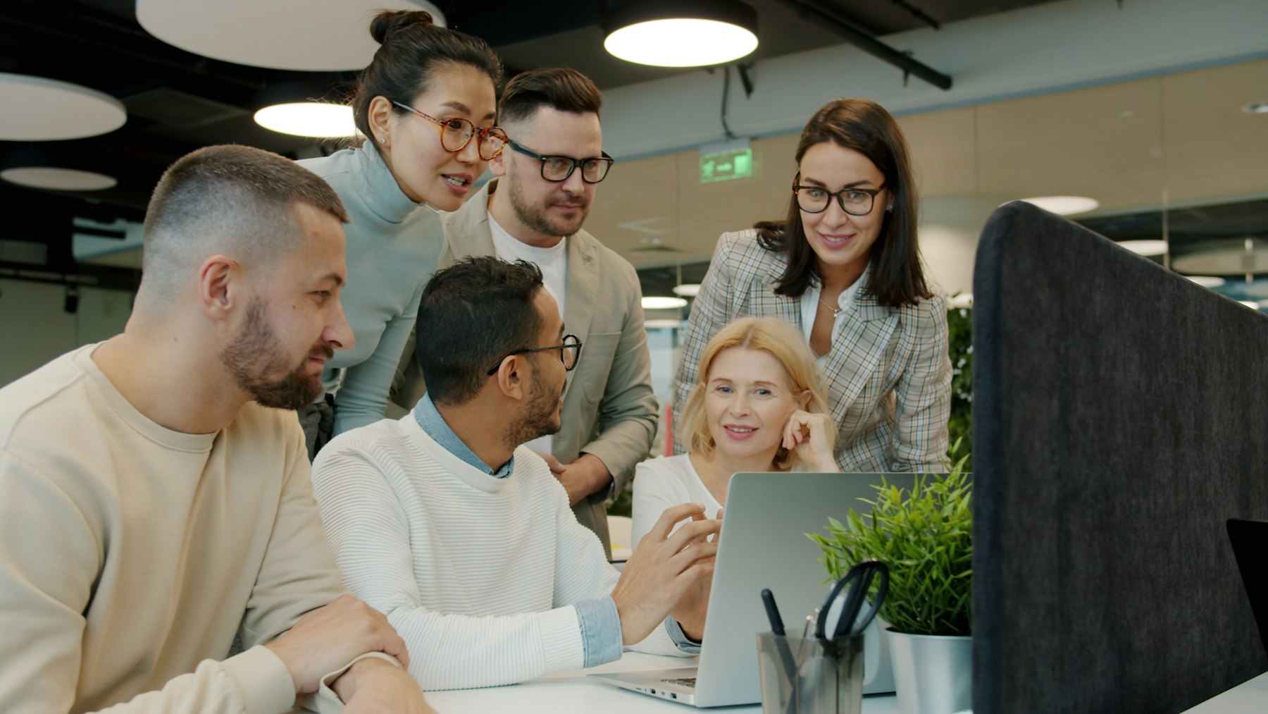 A diverse Alpha Digitals team collaborating closely around a laptop