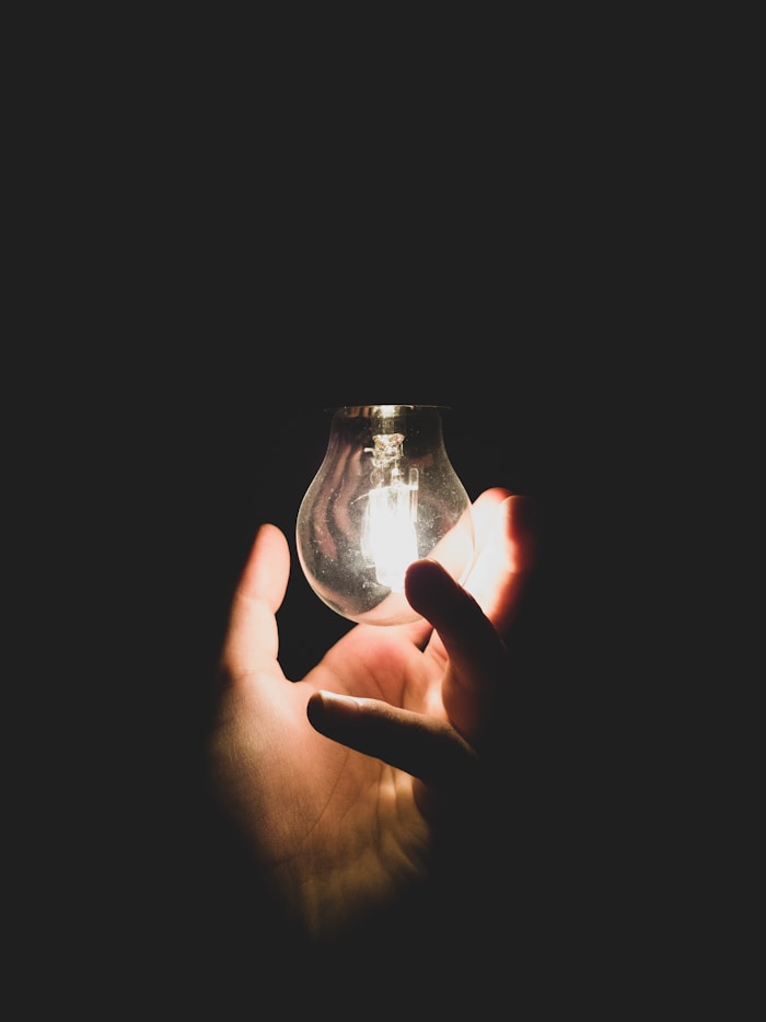 A glowing lightbulb held in hand